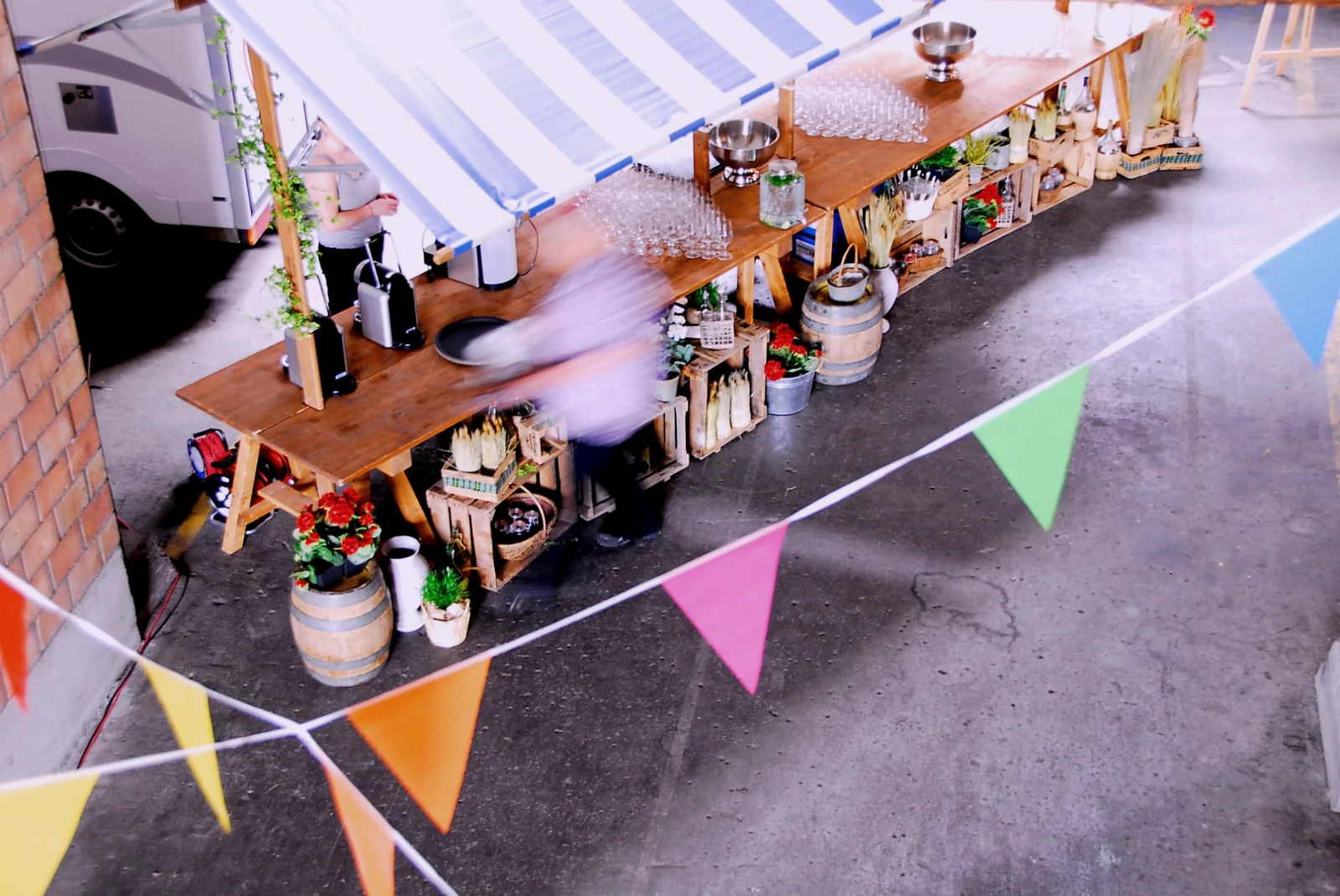 Decorated market stand with wooden tables, parasols and bunting at an event